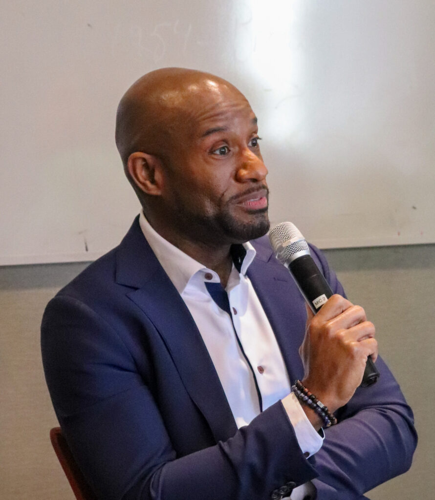 Glenn Jones holds a microphone while addressing the audience.