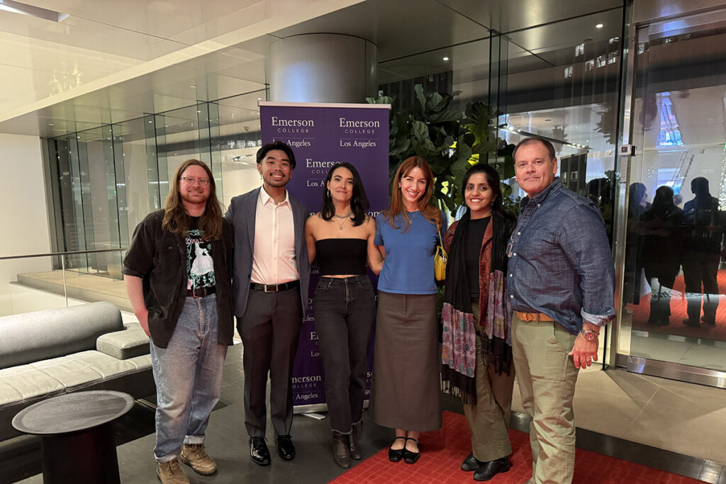 Six men and women stand in front of Emerson banner in ELA building