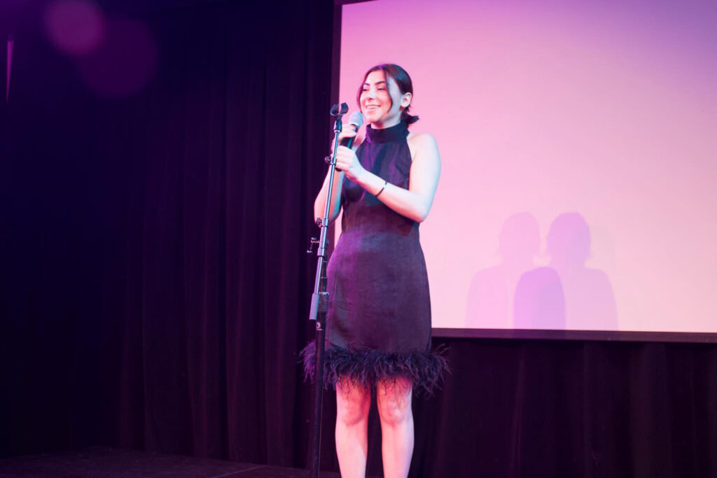 Riley Dewey performs on stage holding a microphone