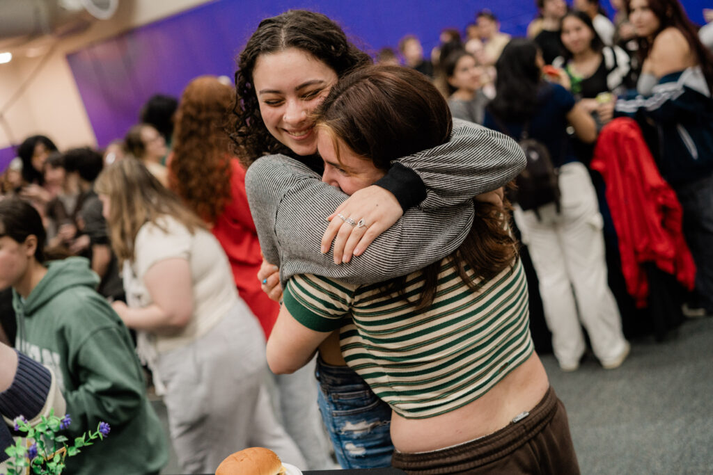 Two people hug each other while smiling