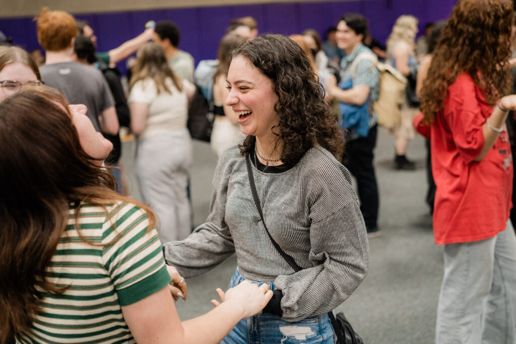 One person holds another person's hands while smiling