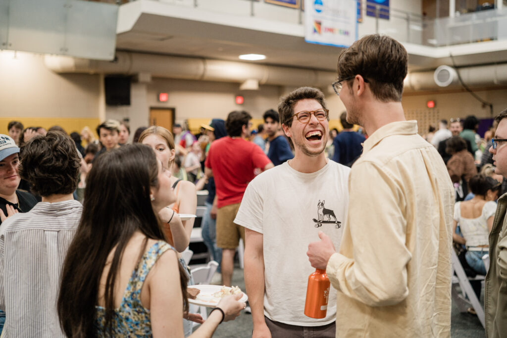 A person smiles widely while talking to two people