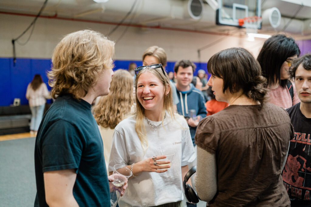 One person smiles while talking to two people