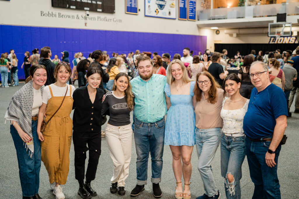 Nine people stand with arms together posing for the camera