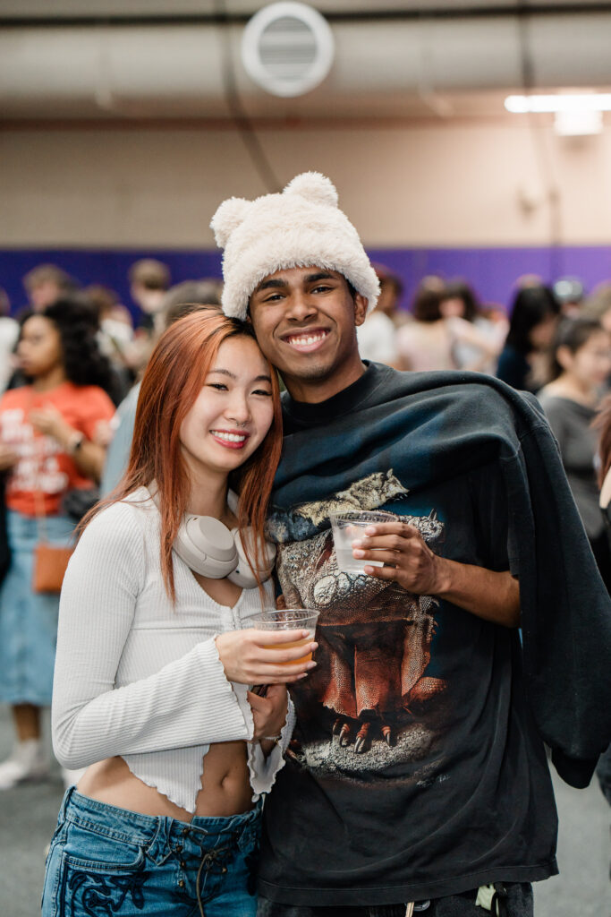 Two people look at the camera while holding drinks