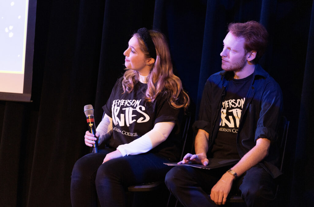 Two people sit listening to the performer