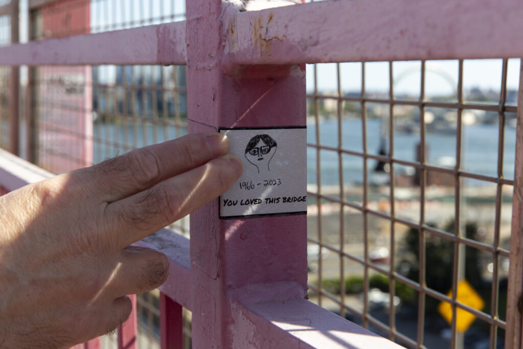 Fingers point at a sticker that says: You loved this bridge