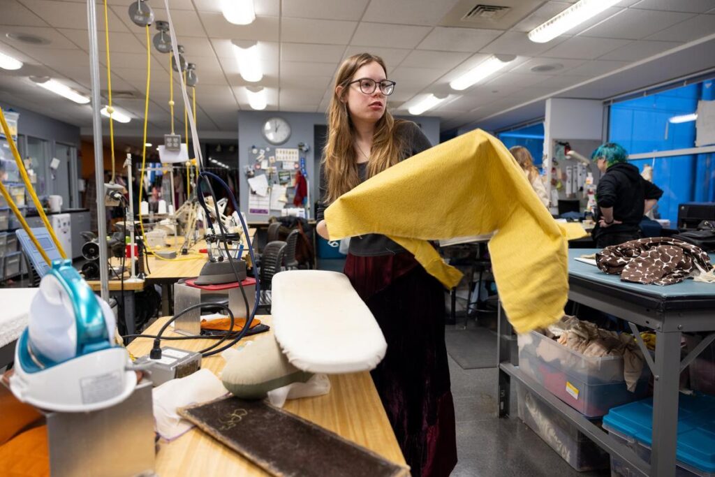 A student holding an ironing board with fabric on it