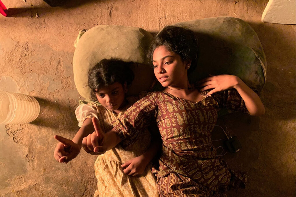 Two young Indian girls lie on floor and point upwards