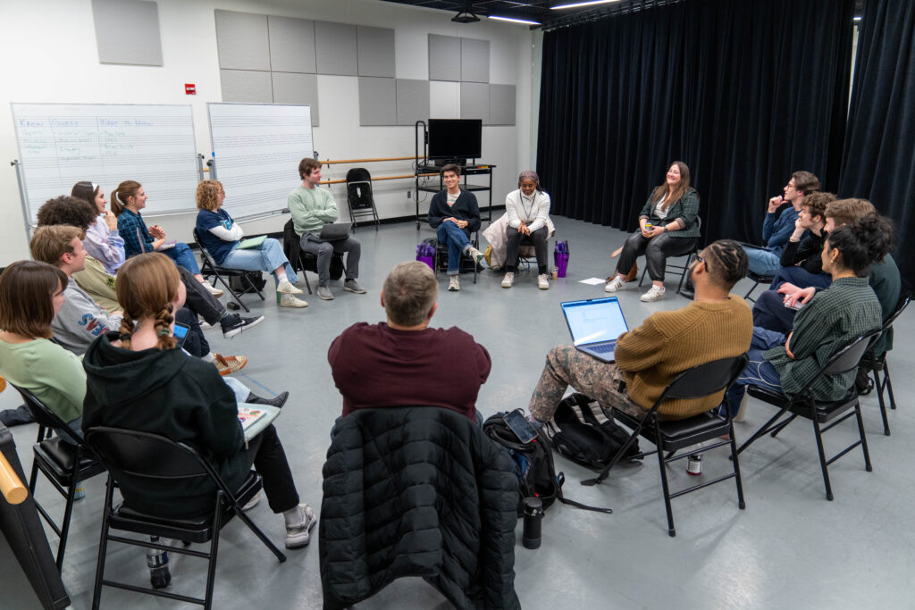A group of people sit on chairs in a circle