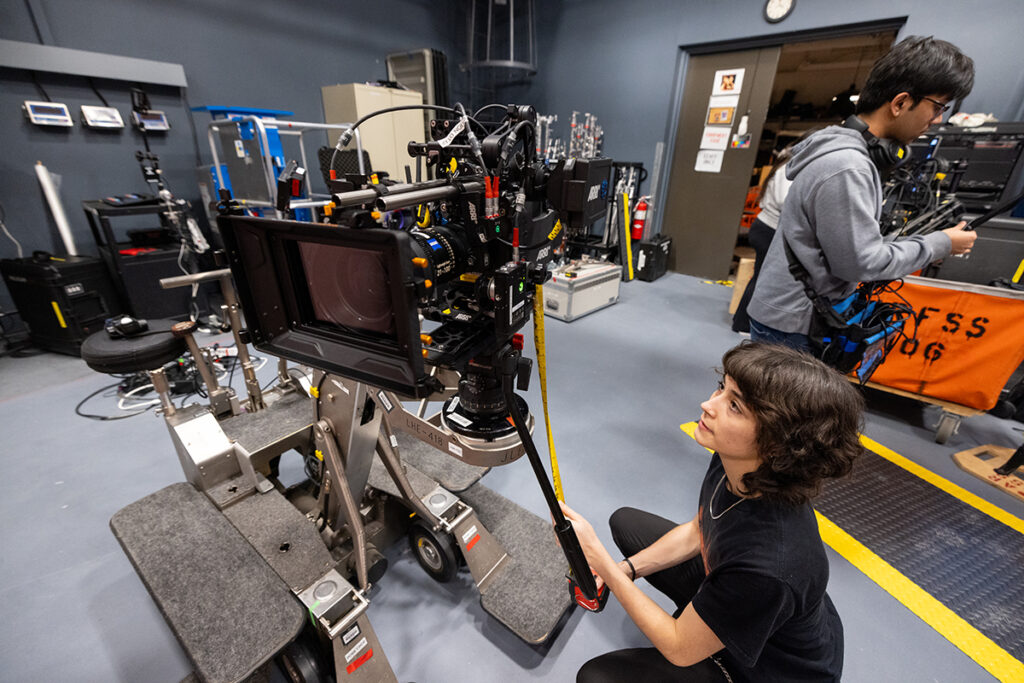 woman crouches down to measure a camera