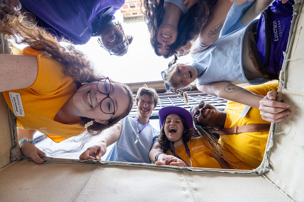 camera looks up at circle of students from inside moving bin