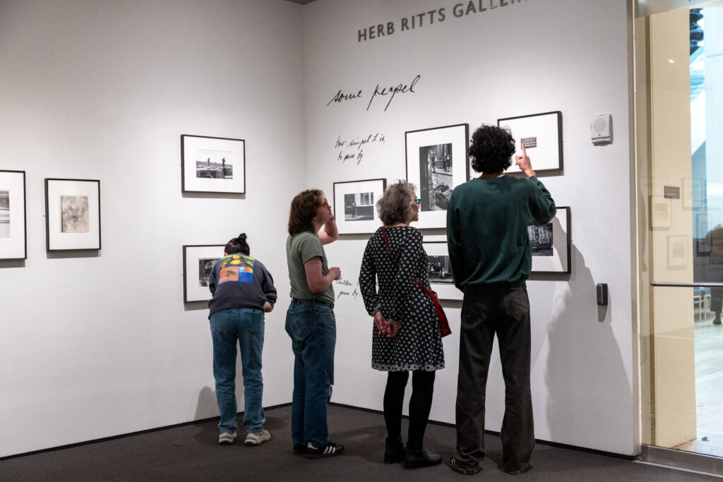 Lauren Shaw looks at art on a wall with her students