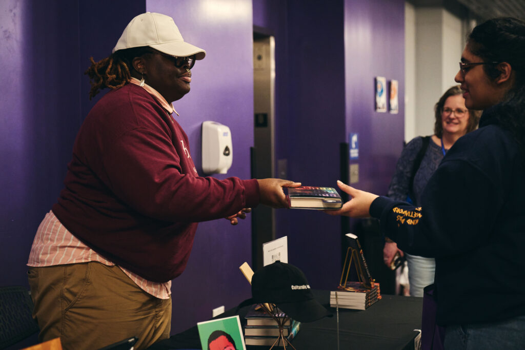 Porsha Olayiwola hands something to someone