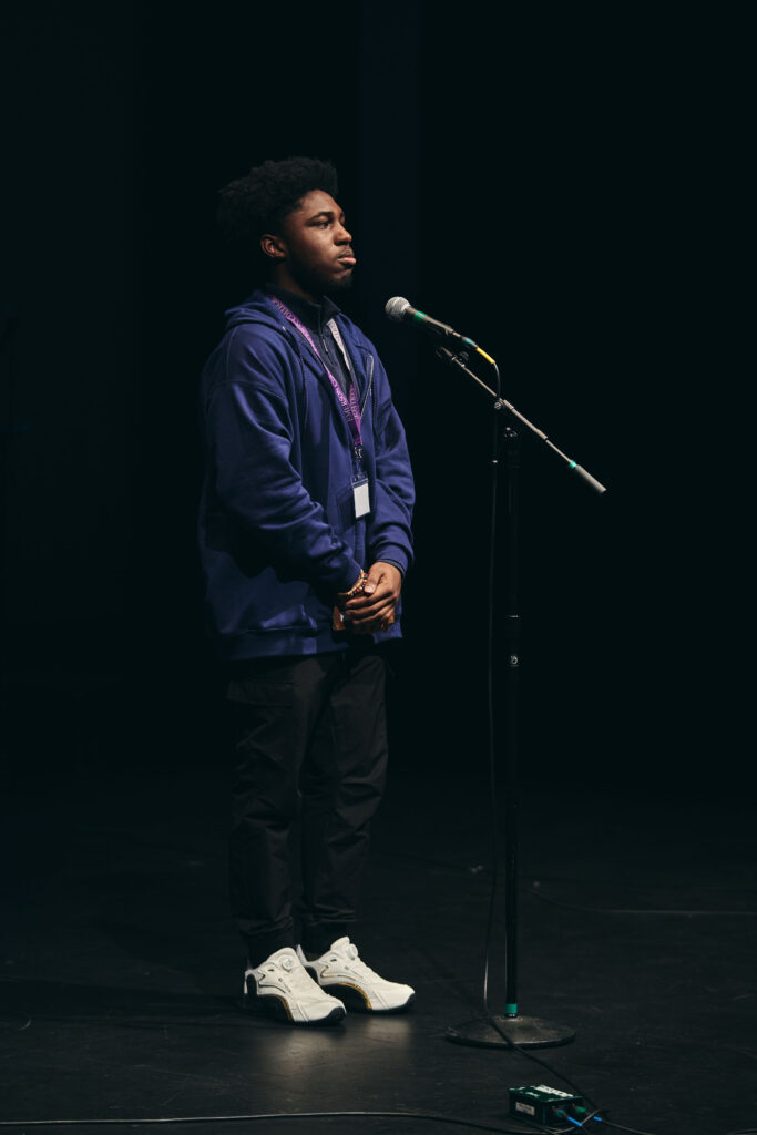 One person stands in front a microphone