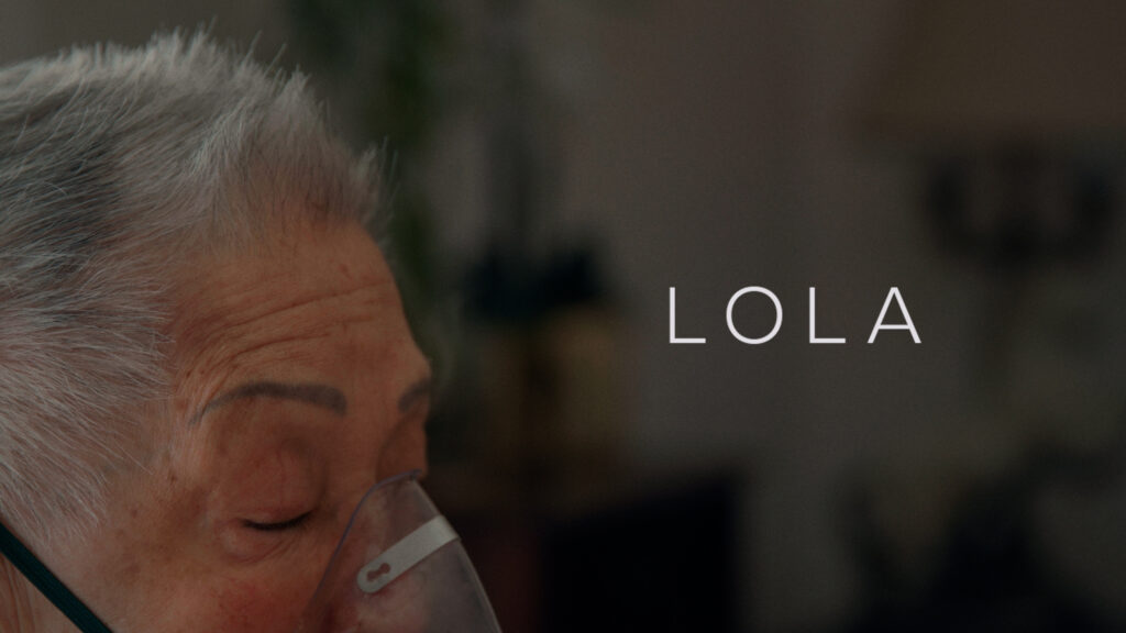 A close-up of a woman with a breathing mask over her face with the film title Lola