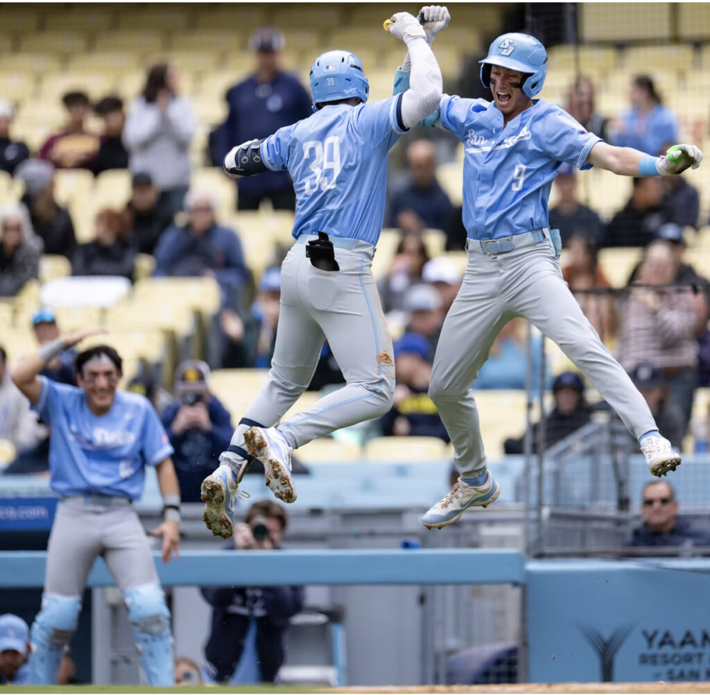 Two baseball players jump up and high five