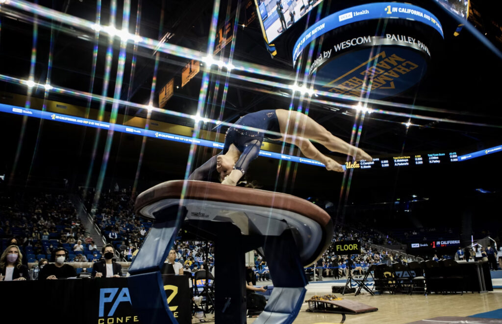 A female gymnast flips on the vault