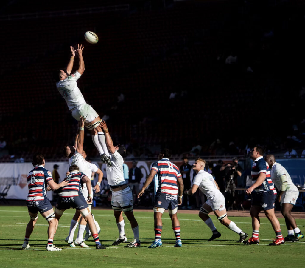 A rugby player is lifted up by him teammates and catches the ball