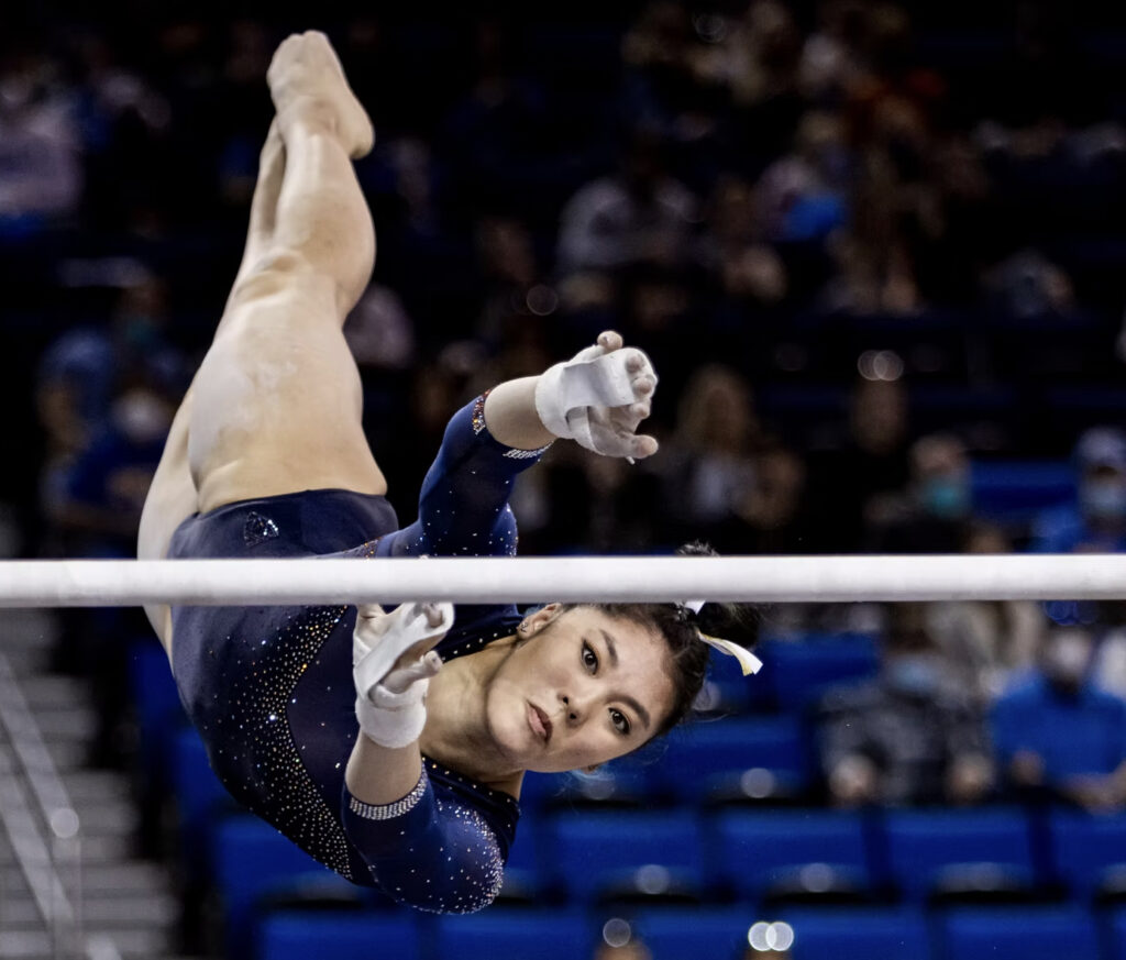 A female gymnast concentrates on catching the uneven bar