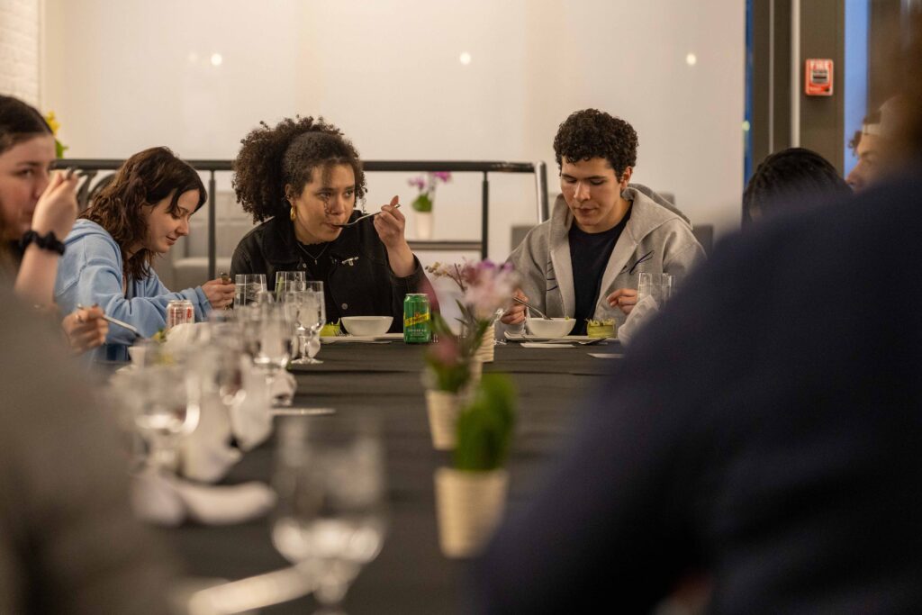 Students sit at a dining table sampling food.
