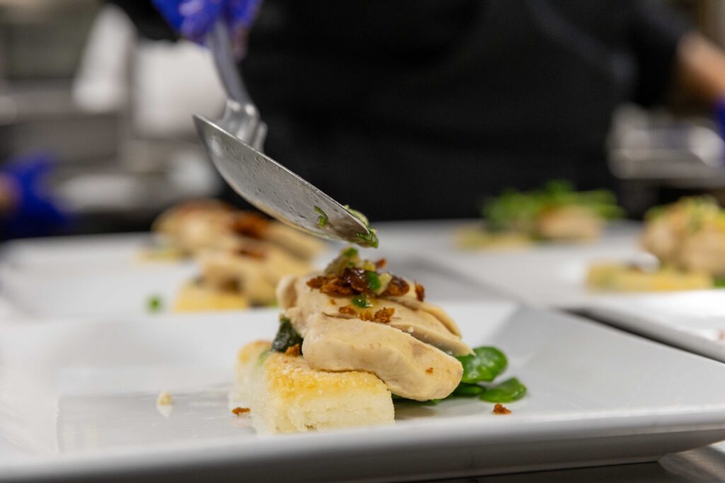 A closeup of a spoon dripping a little sauce on top of food