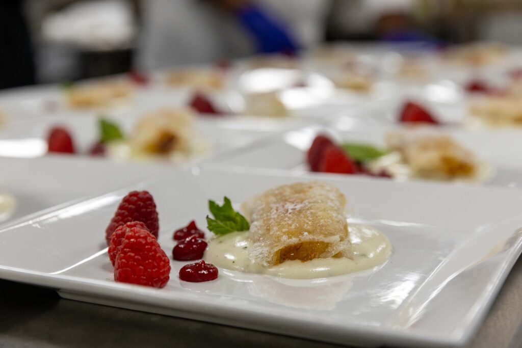Closeup of a dessert with raspberries, and a pastry on top of pudding