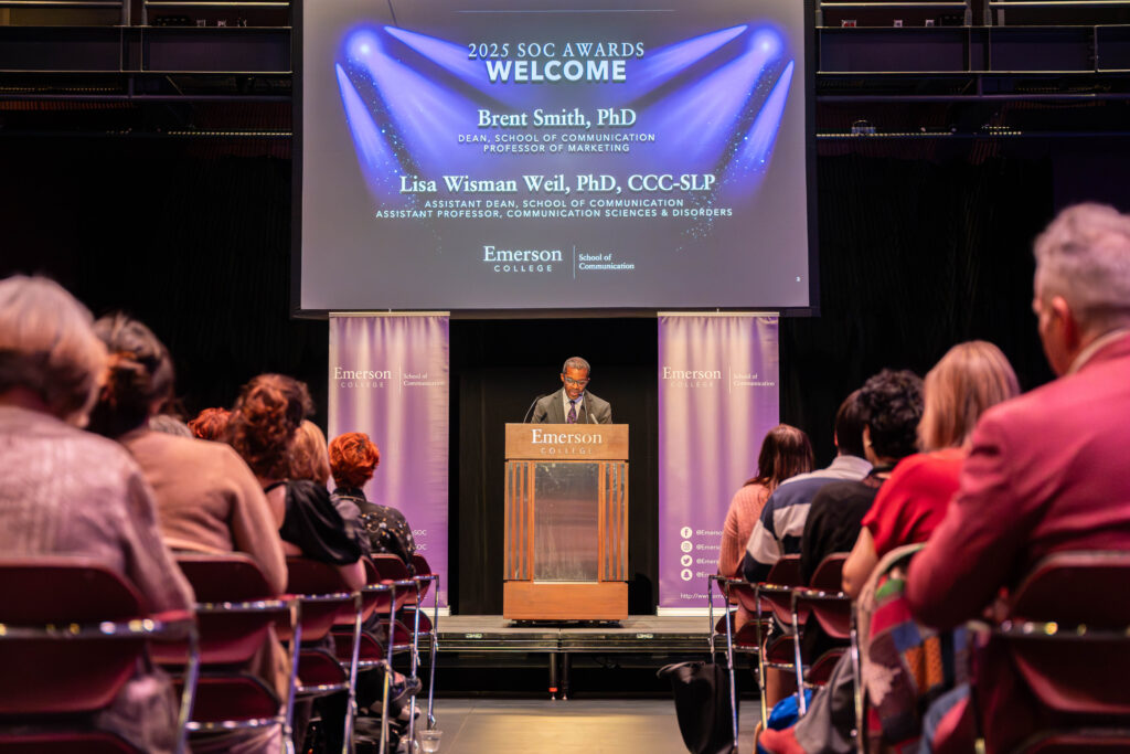 SOC Dean Brent Smith stand behind the podium during the SOC Awards as he welcome a full room of attendees.