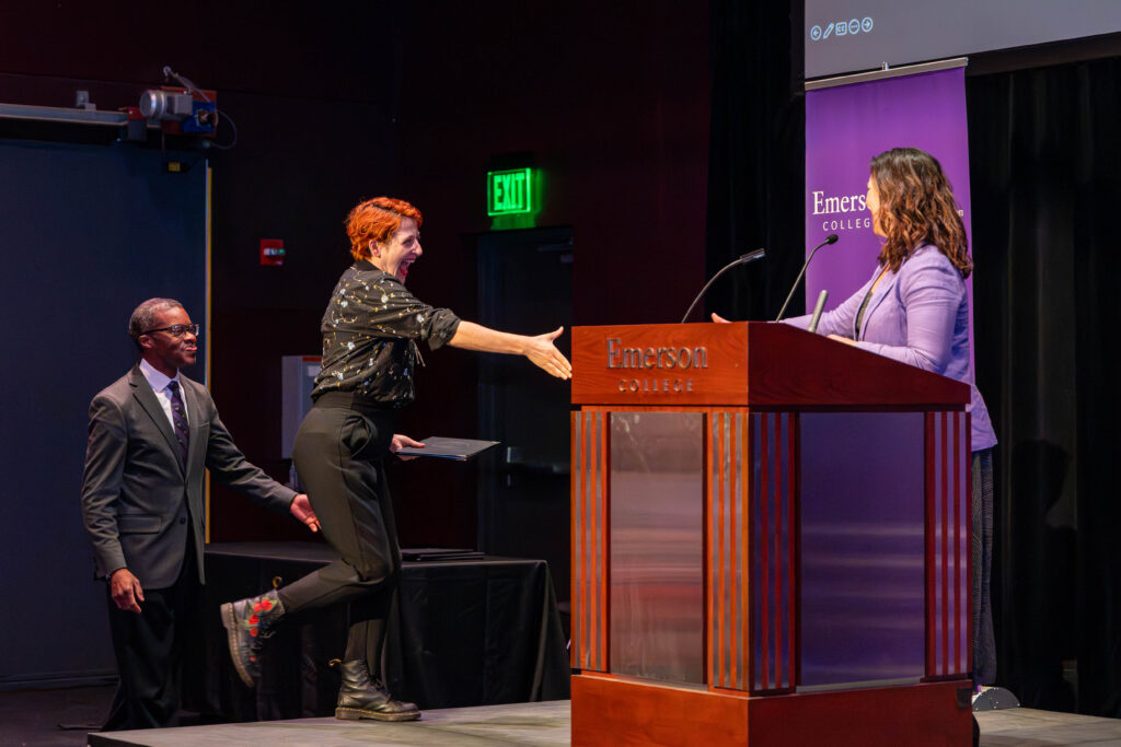 Brent and a smiling students shake hands after they are delivered their award.