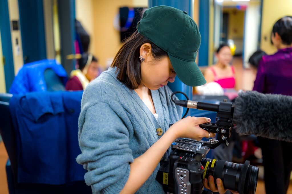 Jing Dong looks through the lens of a video camera
