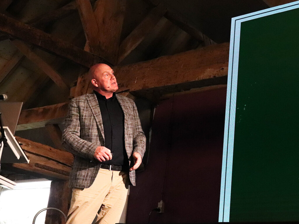 Man in plaid jacket looks up at screen