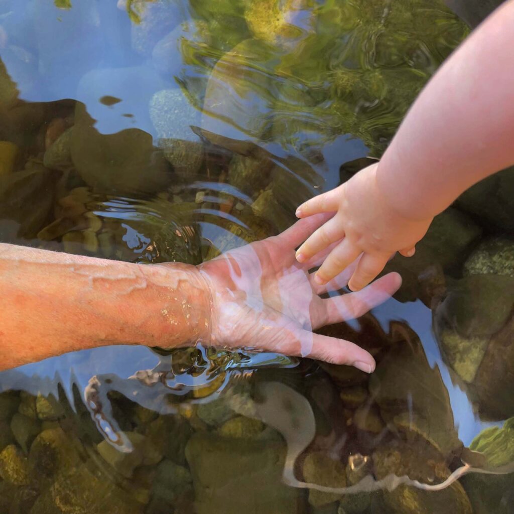 Two hands holding each other while letting go in water