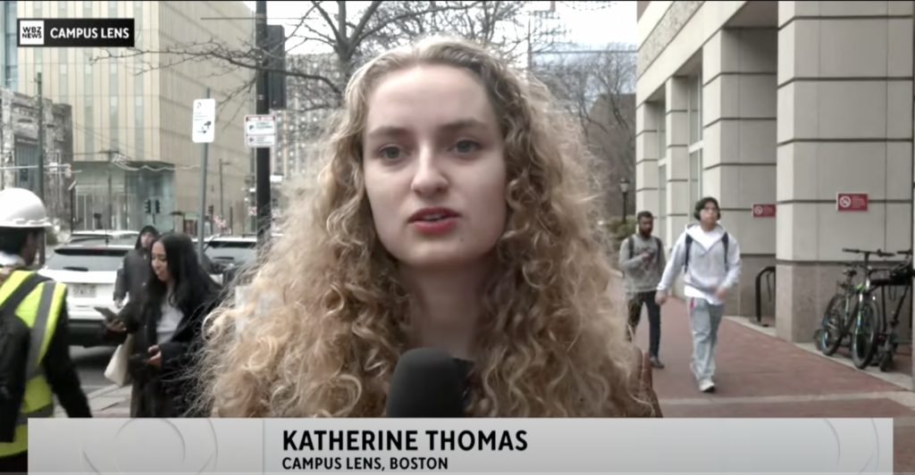 Katharine Thomas holds a microphone while reporting on BU's campus