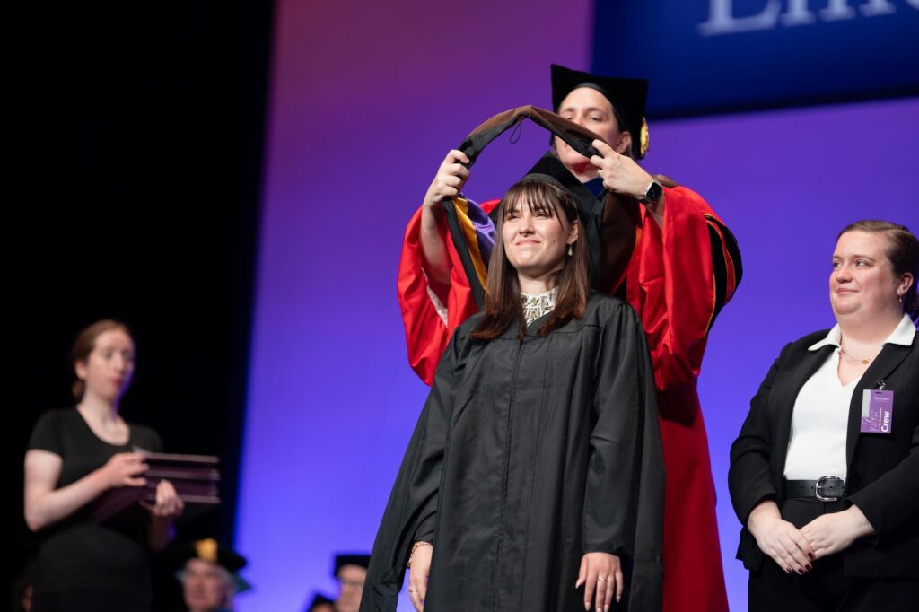 A student gets a sash put over their head