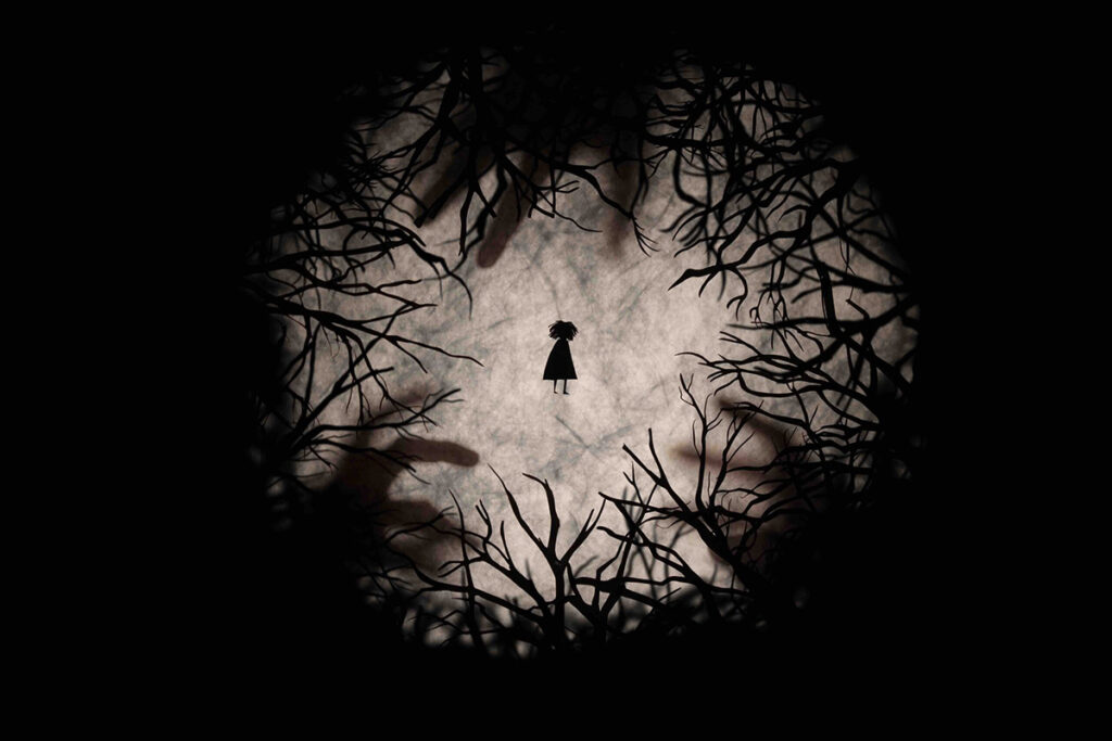 a silhouetted figure is suspended between silhouettes of leafless trees