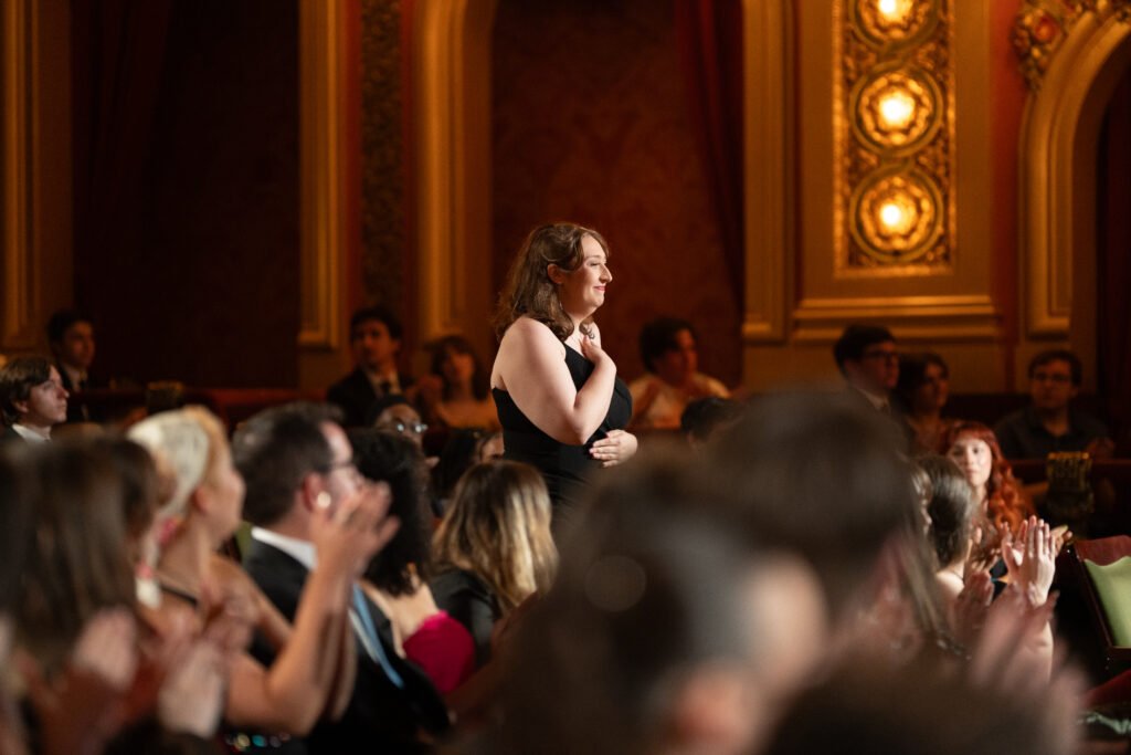 Person standing up to accept award in audience