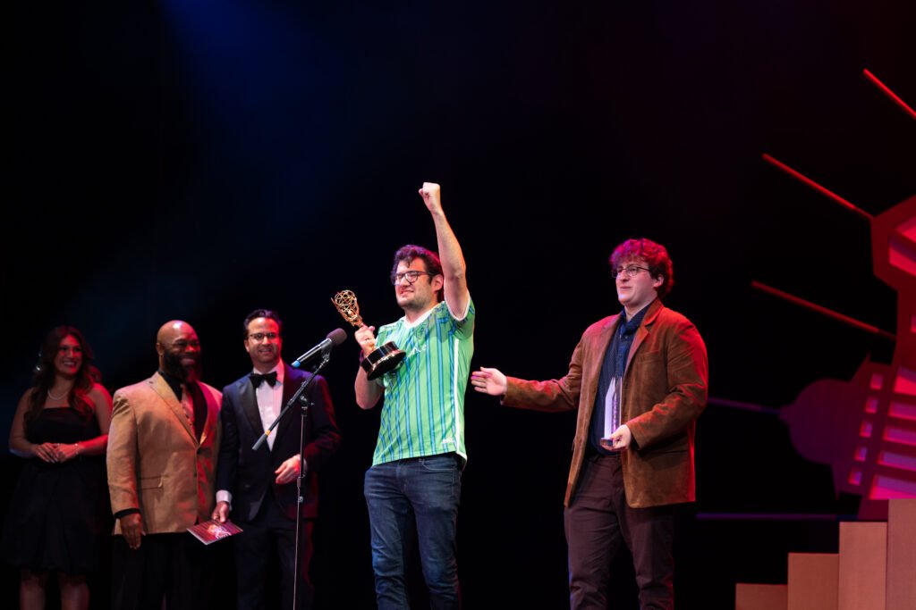 A person raises their arm in triumph while accepting an award