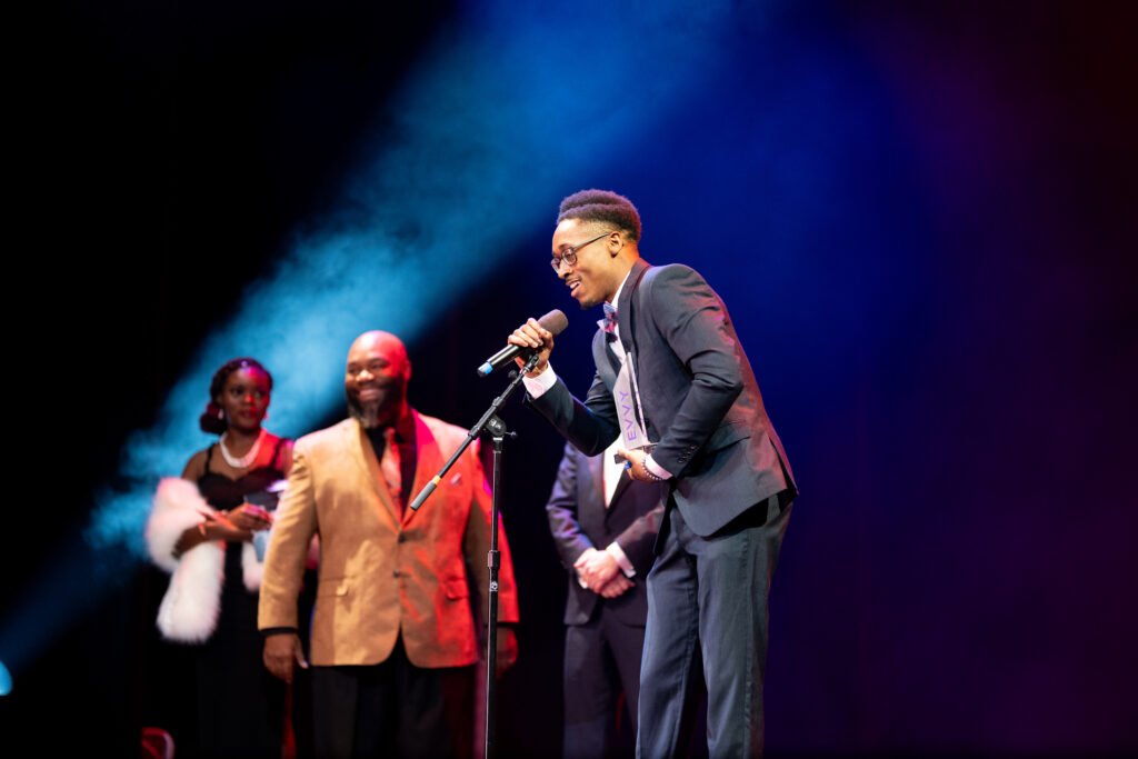 A person speaks on stage while holding the microphone