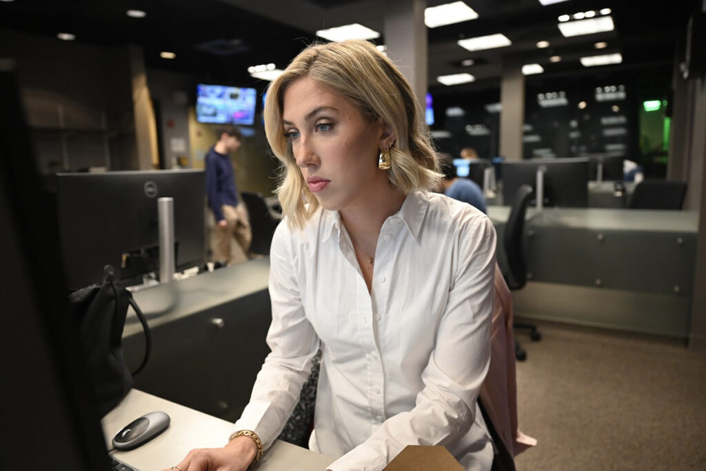 Faith Pinnow works at a laptop in the Journalism production center