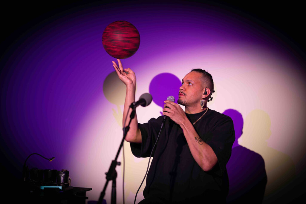 Man speaks into mic while spinning a ball on his other hand