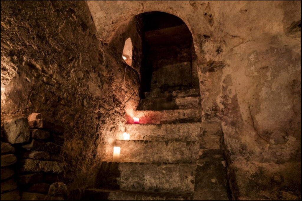 steep stone steps in an ancient cellar illuminated by candles