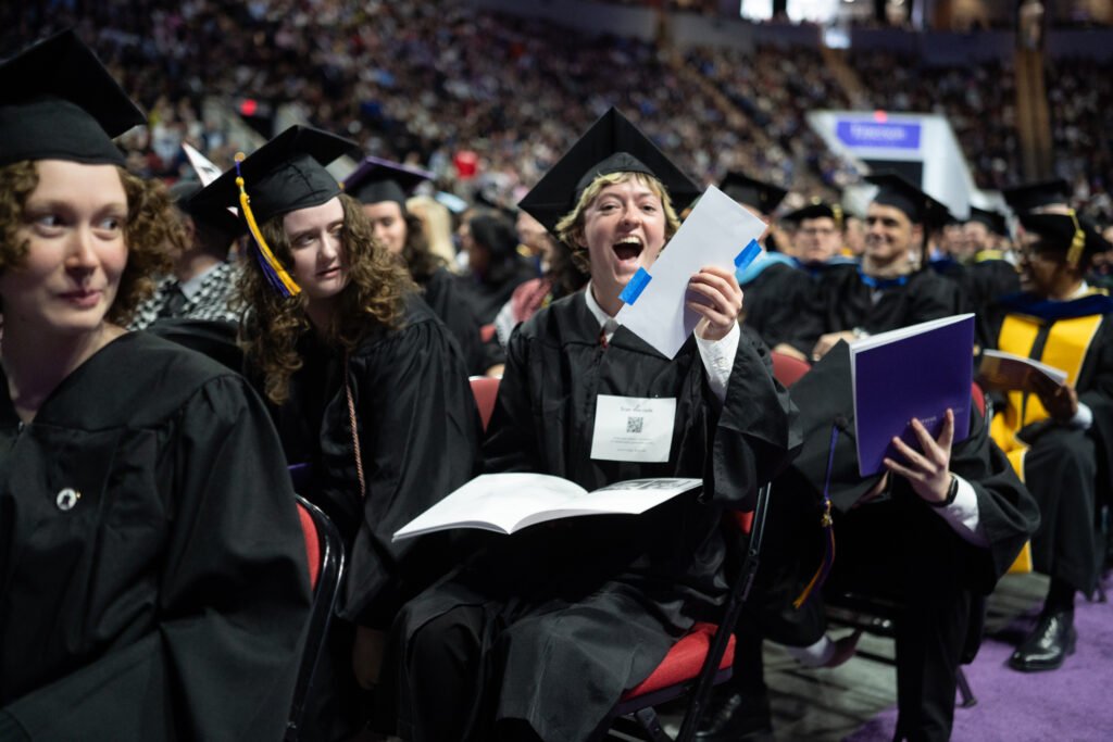 A student holds up an envelope after finding a lottery ticket taped to the bottom of their seat.