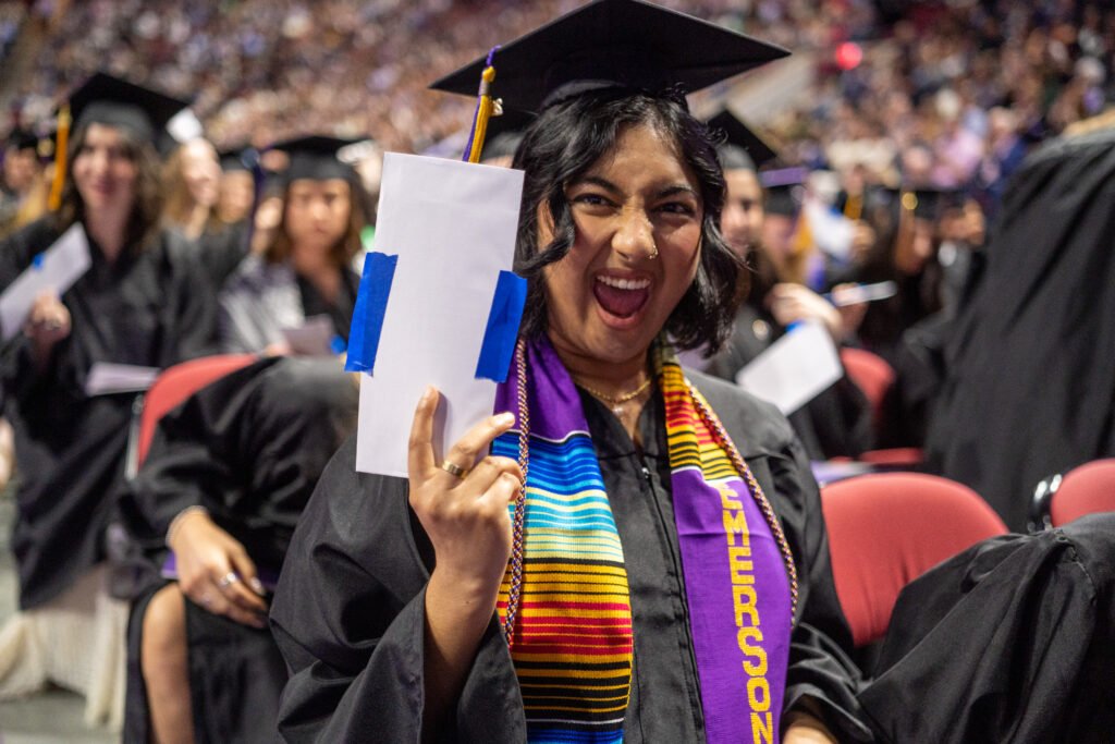 A student smiles while holding up an envelope with a lottery ticket in it
