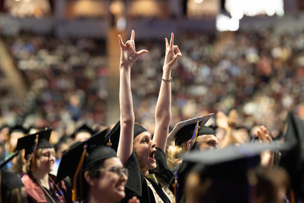 A student raises her hands and yells in triumph