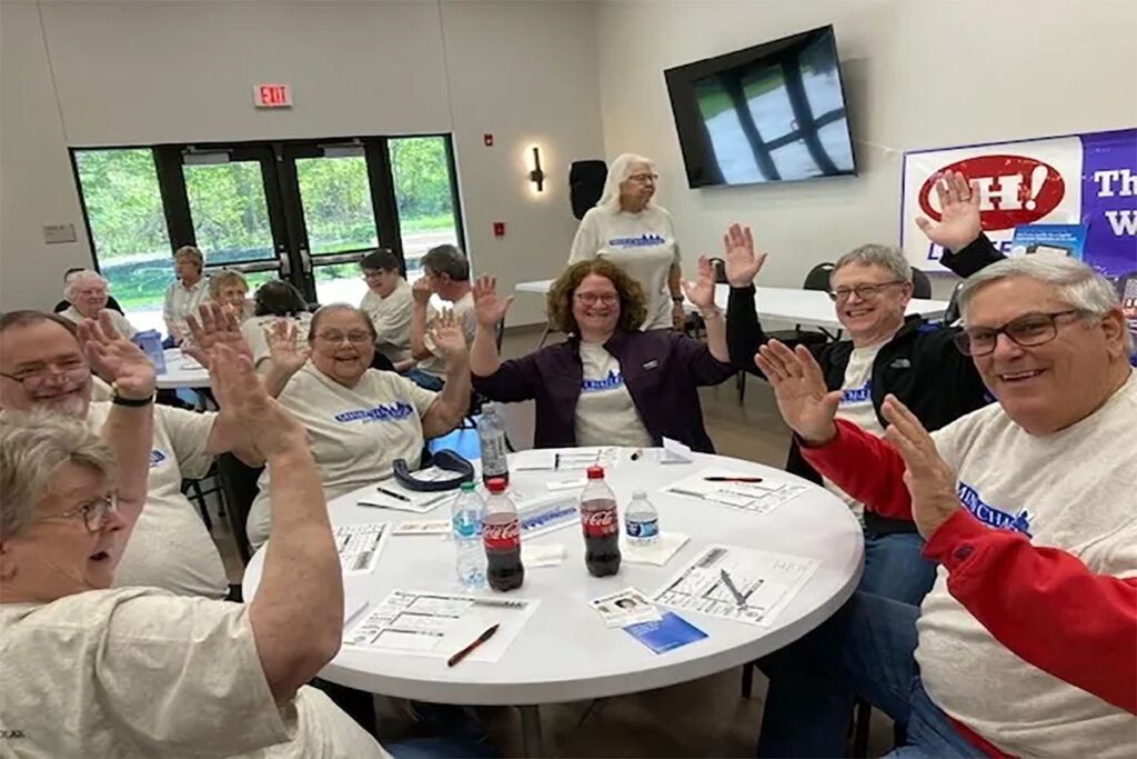 People sit around in a circle with hands up