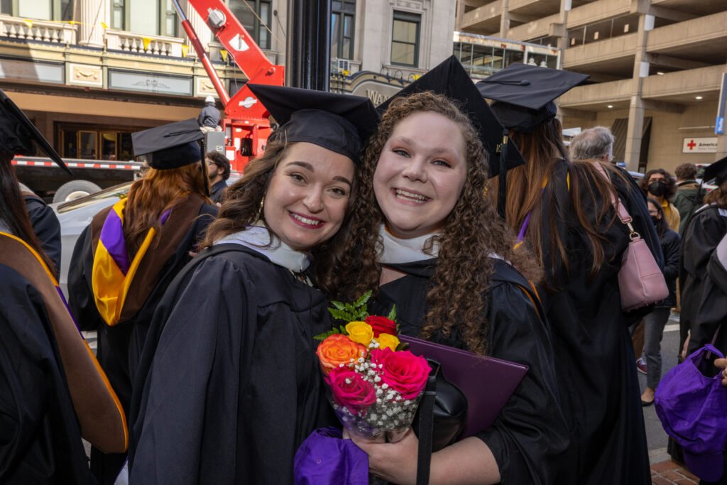 Two grads pose for photo.