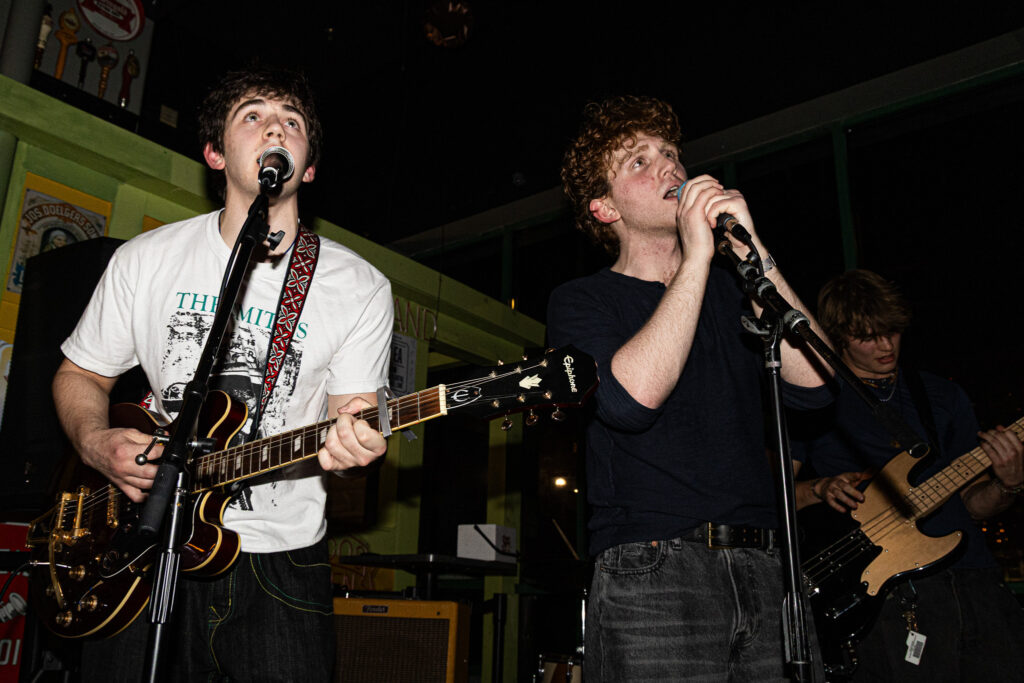Charlie Silver plays guitar while Jack Silver sings into a microphone