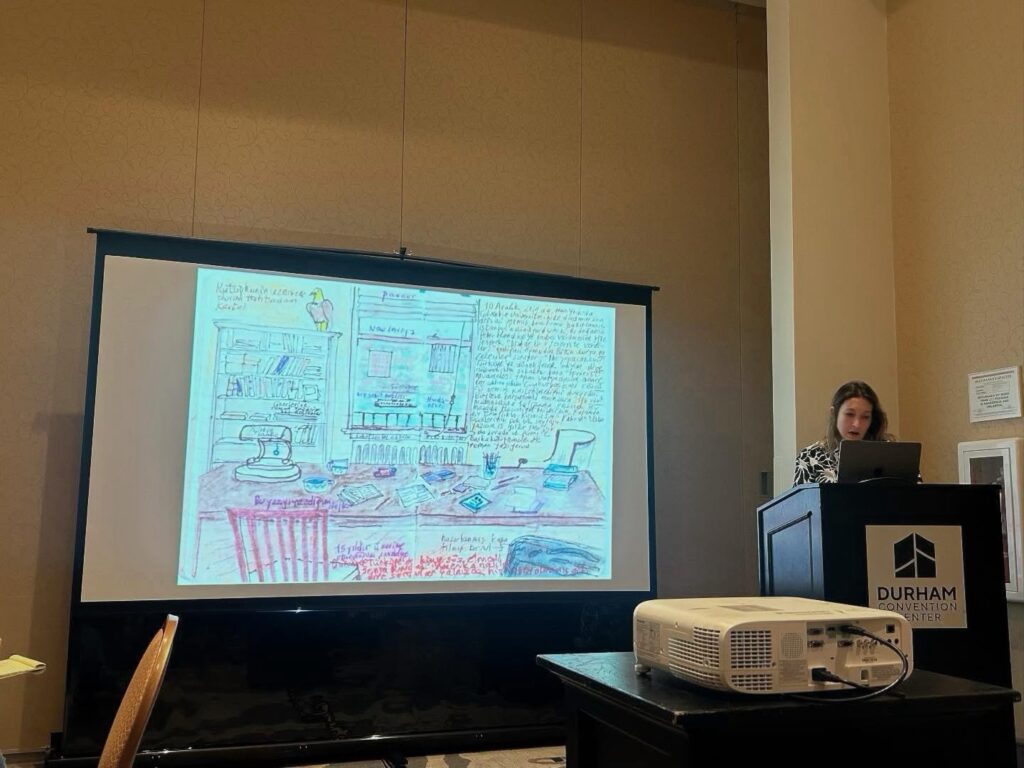 Pelin K?vrak speaks from a lectern with a projected screen image next to her.