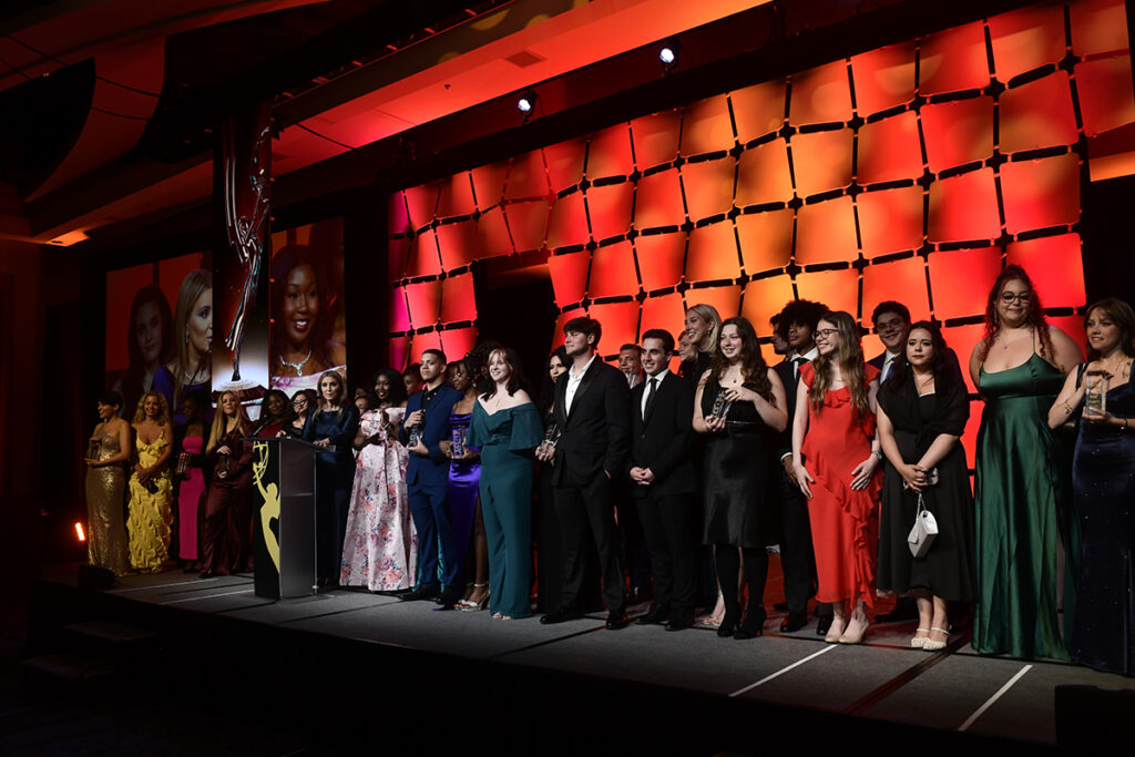 Young people in formal attire line up on stage