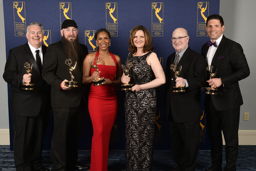 Six men and women hold Emmy Awards